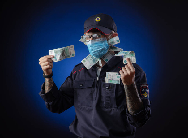 un tipo con un uniforme de policía oficial de policía ruso con una máscara médica con dinero en sus manos. Traducción española de "Police
" - Foto, imagen
