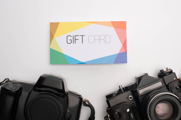 Bovenaanzicht van kleurrijke cadeaukaart en digitale camera 's op witte achtergrond - Foto, afbeelding