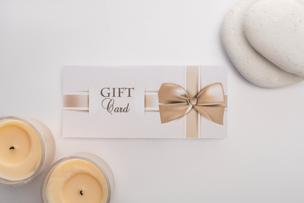 Top view of gift card near candles and zen stones on white background - Foto, Bild