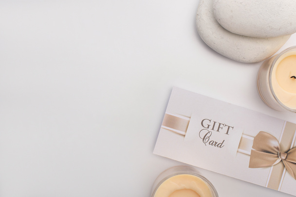 Top view of gift card, zen stones and candles on white background - Fotografie, Obrázek
