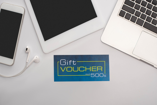 Top view of gift voucher near gadgets on white background - Photo, Image