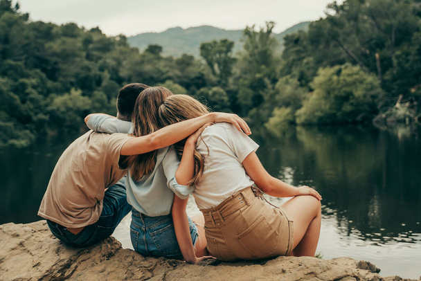 Ystävät halaavat luonnon järvessä keskellä metsää. - Valokuva, kuva