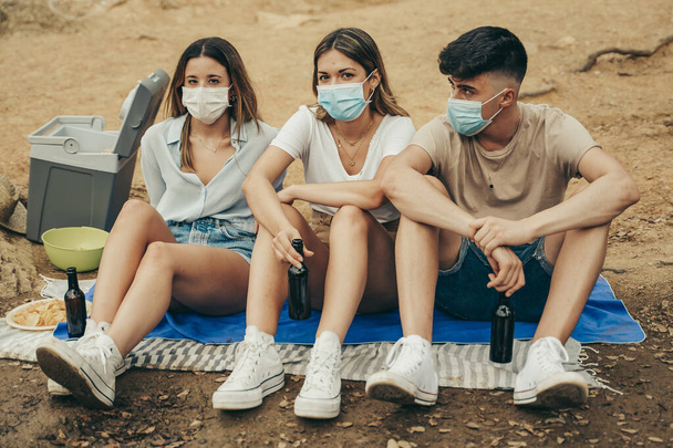 Amigos con máscaras disfrutando de un día de verano en una pandemia de 2020
. - Foto, imagen