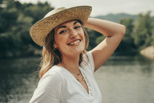 Молода дівчина з ковбойським капелюхом на озері посеред лісу навесні
. - Фото, зображення