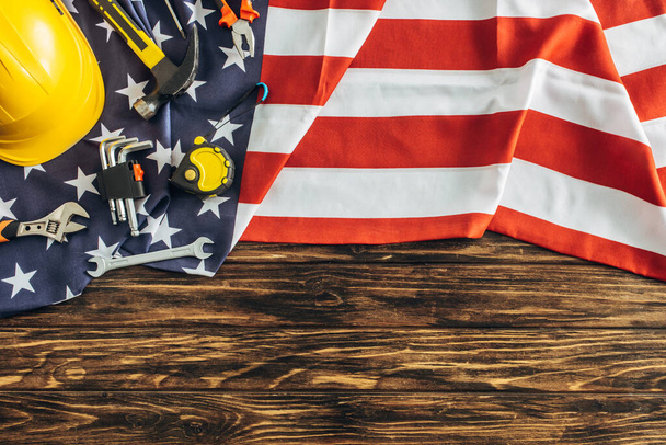 top view of instruments and safety helmet on american flag and wooden surface, labor day concept  - Photo, Image
