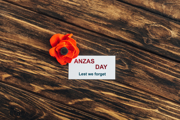 top view of artificial flower near card with anzas day lettering on wooden surface  - Photo, Image