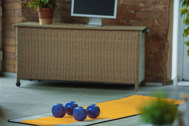 Blue dumbbells lying on yellow yoga mat. Fitness, aerobic. Staying sportive during insulation. - Zdjęcie, obraz