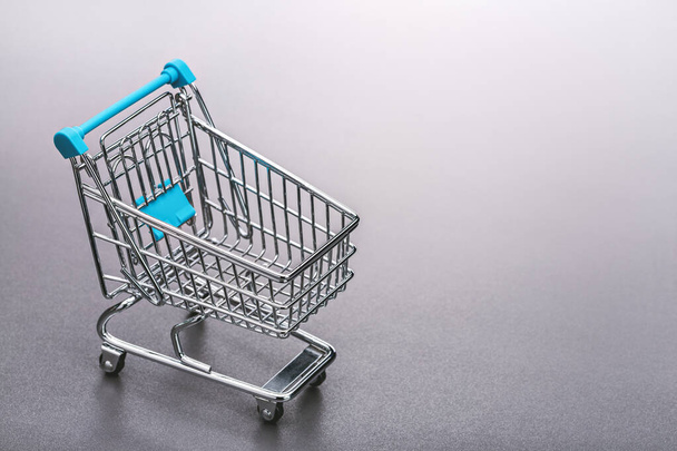 Metal shopping cart (toy). Gray background, copy space. - Фото, изображение