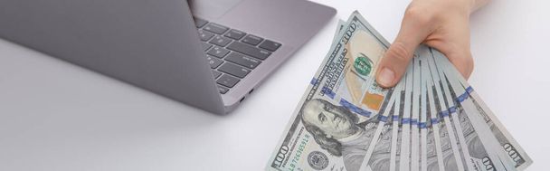 kobieta pracuje na laptopie i pokazuje dolary, widok z bliska - Zdjęcie, obraz