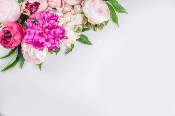Flat lay of flowers and green leaves. Tender Peonies and chrysanthemums bloom pattern, composition for postcards on white background. - Photo, image
