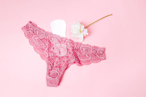 servilleta sanitaria con una hermosa peonía y ropa interior sobre un fondo rosa, cuidado de la salud, protección mensual, amigo confiable - Foto, imagen