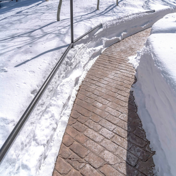 Plaza de piedra camino de ladrillo curvado en medio de la capa profunda de nieve fresca en un día de invierno soleado
 - Foto, imagen