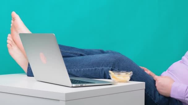 Großaufnahme männlicher Beine auf einem Schreibtisch in der Nähe eines Laptops. Das Konzept der Langeweile und Ermüdung bei der Arbeit. - Filmmaterial, Video