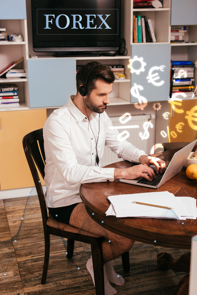 Foco seletivo de freelancer em camisa e calcinha usando fone de ouvido e laptop perto de papéis na mesa em casa, ilustração forex
 - Foto, Imagem