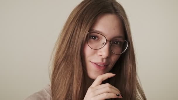 Jovem mulher satisfeita isolada sobre fundo de parede cinza olhando câmera em óculos
 - Filmagem, Vídeo