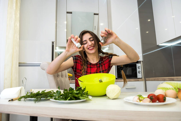 junge Frau bereitet Salat mit Gemüse mit Salz und Pfeffer für besseren Geschmack. - Foto, Bild