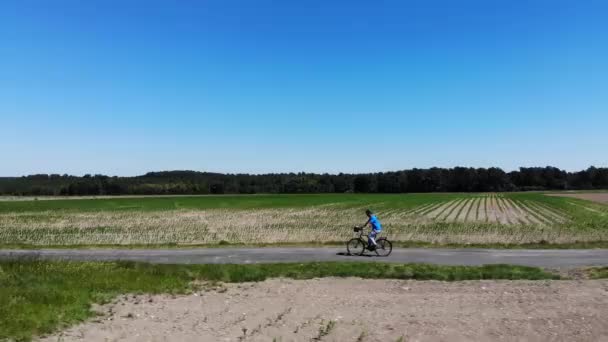 Tanımlanamayan adam yeşil elektrikli bisikletle büyük bir çayırdan geçerken tek bir patikadan hızla geçiyor. Atletik erkek turist tatil gününün tadını çıkarıyor. Manzaralı kırlarda bisiklet sürüyor.. - Video, Çekim