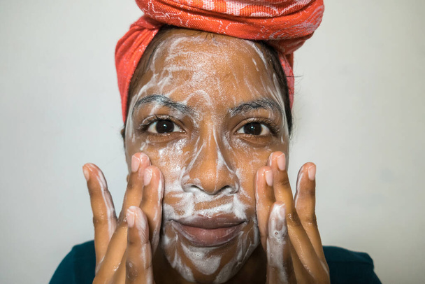 Αφρο-Αμερικανίδα πλένει το πρόσωπό της. Έννοια φροντίδας δέρματος - Φωτογραφία, εικόνα