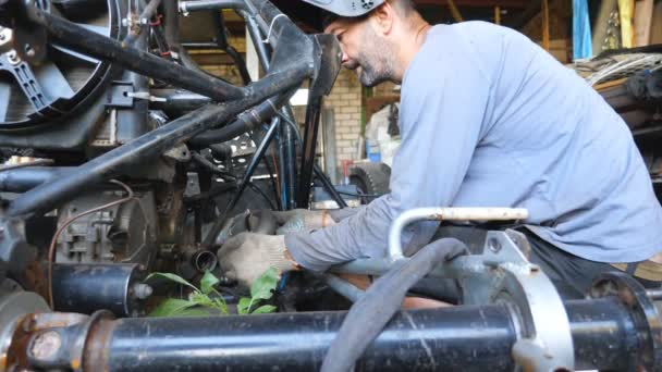 Kaynak maskesi tamir aracındaki yetişkin tamirci. Erkek tamirci otomobili tamir ediyor. Otomobil ustası işini garajda ya da atölyede yapıyor. Adam otomatik servise başladı. Yavaş çekim. Yakın çekim. - Video, Çekim