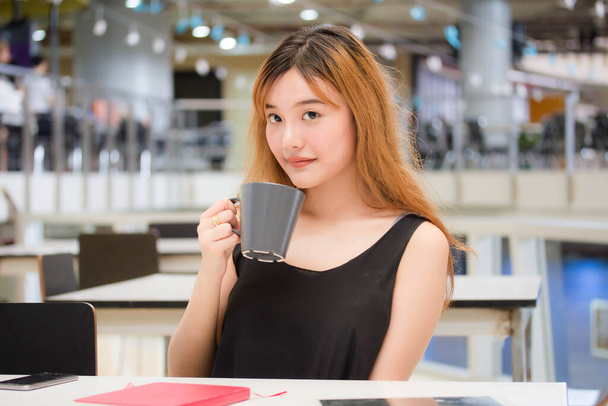 Όμορφη νεαρή ενήλικη ταϊλανδέζα χάλκινα μαλλιά πίνοντας καφέ - Φωτογραφία, εικόνα
