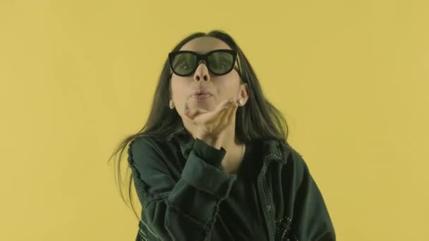 Young beautiful girl makes air kiss on the yellow background - Filmati, video