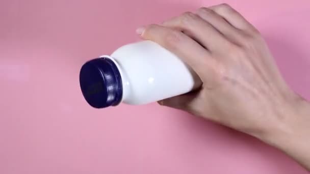 Γυναικείο χέρι περιστρέφει ένα λευκό μπουκάλι στο χέρι - Πλάνα, βίντεο