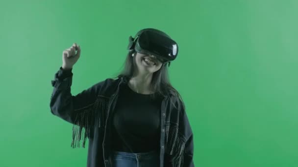 Boldog fiatal, gyönyörű nő táncol a VR headsetben. Virtuális valóság sisak a zöld háttérben. Kroma kulcs - Felvétel, videó