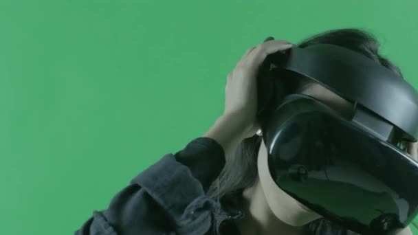 Fiatal gyönyörű zenét hallgatni és táncolni a VR headset. Virtuális valóság sisak a zöld háttérben. Kroma kulcs - Felvétel, videó