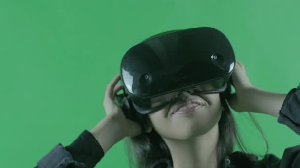 Молодая женщина слушает музыку и танцует в наушниках VR. Шлем виртуальной реальности на зеленом фоне. Ключ хромы
 - Кадры, видео