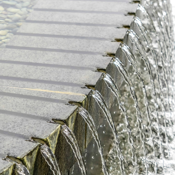 Quadratischer Rahmen Nahaufnahme des runden steinernen Poolbrunnens mit glitzerndem klarem Wasser - Foto, Bild