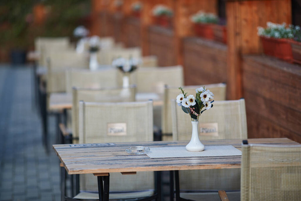 mesas y sillas en la terraza, jarrones con margaritas
  - Foto, imagen