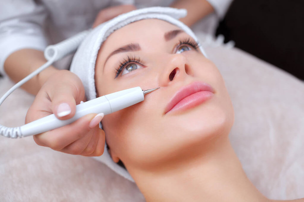 Врач-косметолог проводит процедуру купероза кожи лица красивой молодой женщины в салоне красоты.
. - Фото, изображение