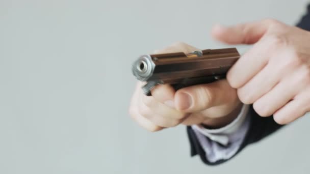 Een zakenman in een jasje met een pistool in zijn hand herlaadt de bout en is klaar om te schieten - Video