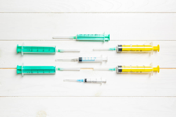 Vista superior de seringas médicas com agulhas em fundo de madeira com espaço de cópia. Conceito de tratamento por injeção
. - Foto, Imagem