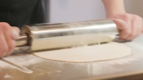Italiaanse pizzakoks die het deeg op een met bloem bestrooide ondergrond vormen en een deeg uitrollen - Video