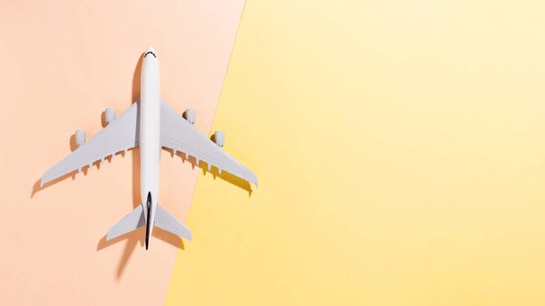 Açık sarı ve turuncu renkli kağıttan arka planda model uçak. Düz konum, üst görünüm ve metin için boşluk kopyala - Fotoğraf, Görsel