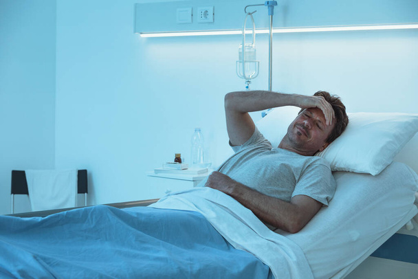 Aikuinen mies makaa sairaalassa yöllä ja hän kärsii - Valokuva, kuva
