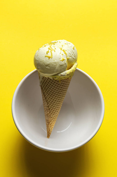 Homemade and refreshing natural lemon ice cream ball in cone on white background - Foto, Imagen