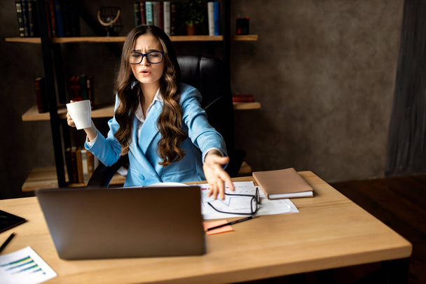 young woman in eyeglasses working at laptop in office - 写真・画像