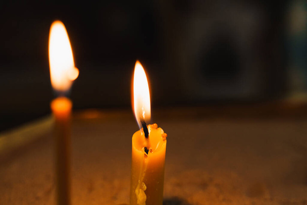 Brûler des bougies en gros plan sur fond sombre à l'église. Une tragédie. Tradition orthodoxe et foi. Équipement pour prier. Priez pour la vie des gens. Priez Dieu - Photo, image