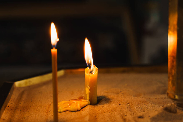 Спалювання свічок на темному фоні в церкві. Трагедія. Православна традиція і віра. Обладнання для молитви. Моліться за життя людей. Молися до Бога - Фото, зображення