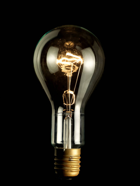 Transparent light bulb turned on on black background - Photo, Image