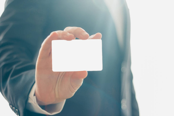 Vista de cerca de la mano del hombre sosteniendo la tarjeta de visita vacía sobre fondo blanco brillante. Copiar espacio
 - Foto, imagen