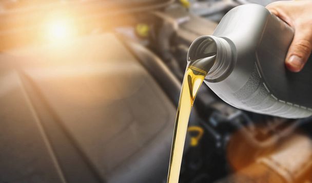 Versare olio a mano sul motore dell'auto, olio fresco versato durante il cambio dell'olio su un'auto
. - Foto, immagini