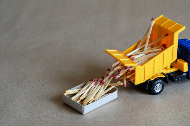 Un camion à benne à jouets jaune renverse des allumettes. Un camion-jouet décharge un corps complet d'allumettes en bois. Contexte industriel créatif. Thèmes logistiques. Concentration sélective
. - Photo, image