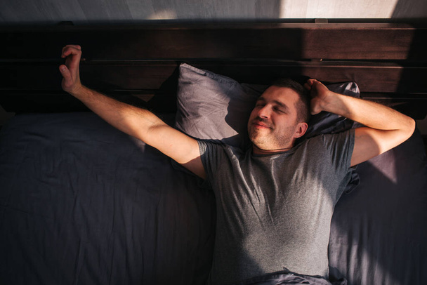 A man in his bed in the morning. He is stretching. Great start to the day - Foto, imagen