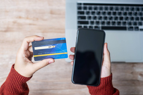 γυναίκα χέρι κρατώντας πιστωτική κάρτα με τη χρήση smartphone και laptop για online αγορές, ενώ κάνοντας παραγγελίες στο σπίτι. επιχείρηση, τρόπος ζωής, τεχνολογία, ηλεκτρονικό εμπόριο, ψηφιακή τραπεζική και έννοια των online πληρωμών - Φωτογραφία, εικόνα