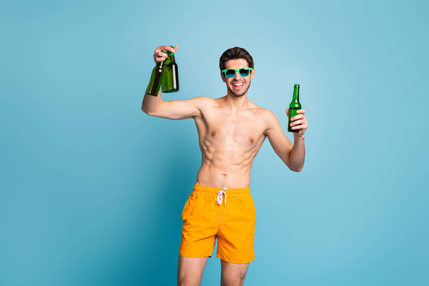 Photo of cheerful positive handsome man holding several bottle of beer smile toothy isolated pastel blue color background - Valokuva, kuva