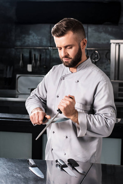 Chef male with knives at kitchen restaurant. Cooker in uniform sharp knife. - 写真・画像