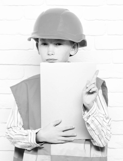 young cute builder boy on white brick wall background - Foto, Bild